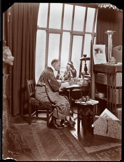 Will R. Barnes in una veste, seduto alla sua scrivania nel suo studio, 1903 da Byron Company